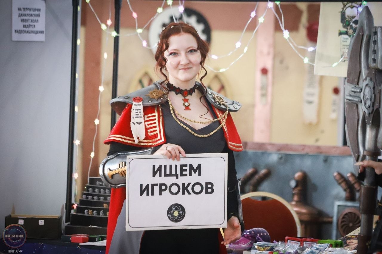 Косплеерша в образе комиссара Warhammer с табличкой «Ищем игроков»